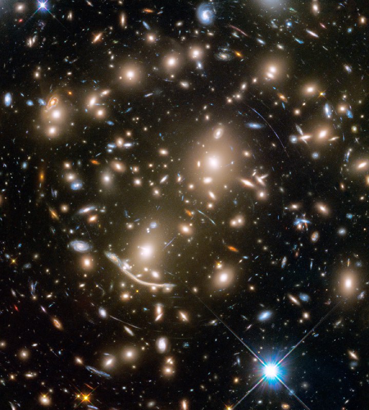 Some 4 billion light-years away, massive galaxy cluster Abell 370 is captured in this sharp Hubble Space Telescope snapshot. The cluster of galaxies only appears to be dominated by two giant elliptical galaxies and infested with faint arcs. In reality, the fainter, scattered bluish arcs, along with the dramatic dragon arc below and left of center, are images of galaxies that lie far beyond Abell 370. About twice as distant, their otherwise undetected light is magnified and distorted by the cluster's enormous gravitational mass, overwhelmingly dominated by unseen dark matter. Providing a tantalizing glimpse of galaxies in the early universe, the effect is known as gravitational lensing. A consequence of warped spacetime, lensing was predicted by Einstein almost a century ago. Far beyond the spiky foreground Milky Way star at lower right, Abell 370 is seen toward the constellation Cetus, the Sea Monster. It was the last of six galaxy clusters imaged in the Frontier Fields project.