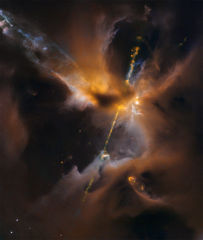 Herbig-Haro 24تشبه هذه الصورة سيفاً مزدوج النصل، لكن هذه النفاثات الكونية تتدفق من نجم حديث الولادة في مجرة قريبة. الصورة، التي تم إنشاؤها من بيانات تلسكوب هبل، تُظهر مشهداً رائعاً يمتد بطول نصف سنة ضوئية عبر Herbig-Haro 24 (HH 24)، التي تبعد حوالي 1300 سنة ضوئية في سُحُب الجزيئات ضمن مجمع أورايون B. يُحيط بالنجم المركزي المخفي غبار وغاز بارد مشكلاً قرصاً دواراً. مع سقوط المادة من القرص نحو الكائن النجمي الشاب، ترتفع درجة حرارتها. يتم قذف نفاثات متعاكسة على طول محور دوران النظام، مما يؤدي إلى إنتاج واجهات صدمية مضيئة أثناء انقطاعها عبر المادة بين النجوم.